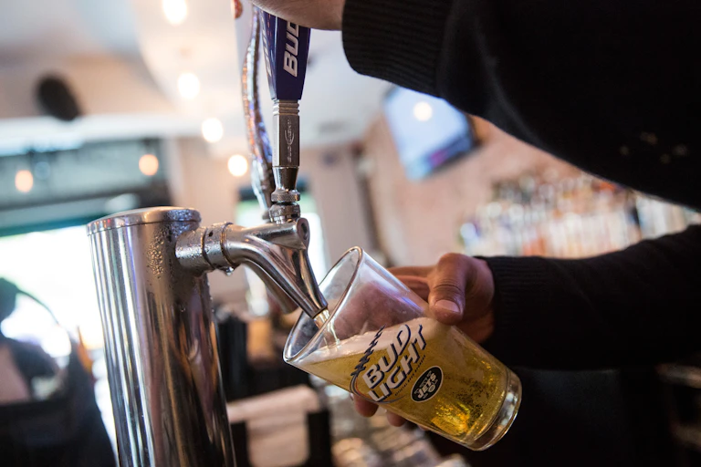 A bartender pours a beer into a Bud Light glass