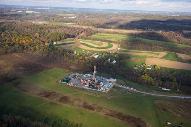 Fracking operation on a concrete slab surrounded by hills and farm fields.