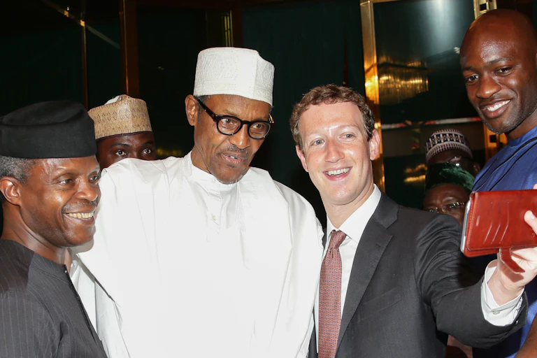 Man wearing a suit and tie takes a selfie with three other men