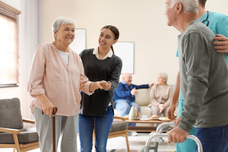 Care staff helping elderly people walk