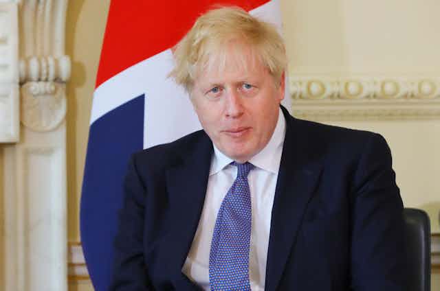 Boris Johnson sitting in front of a union flag. 