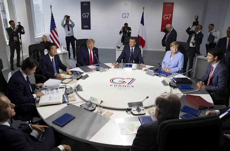 G7 leaders sit around a circular table at the 2019 summit in Biarritz. Visible leaders are Shinzo Abe, Donald Trump, Emmanuel Macron, Angela Merkel, and Justin Trudeau.