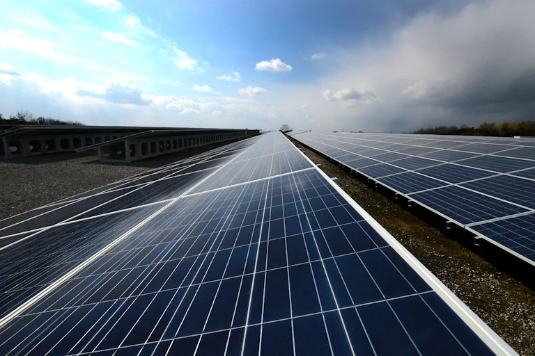 Dark solar panels lie under a blue cloudy sky