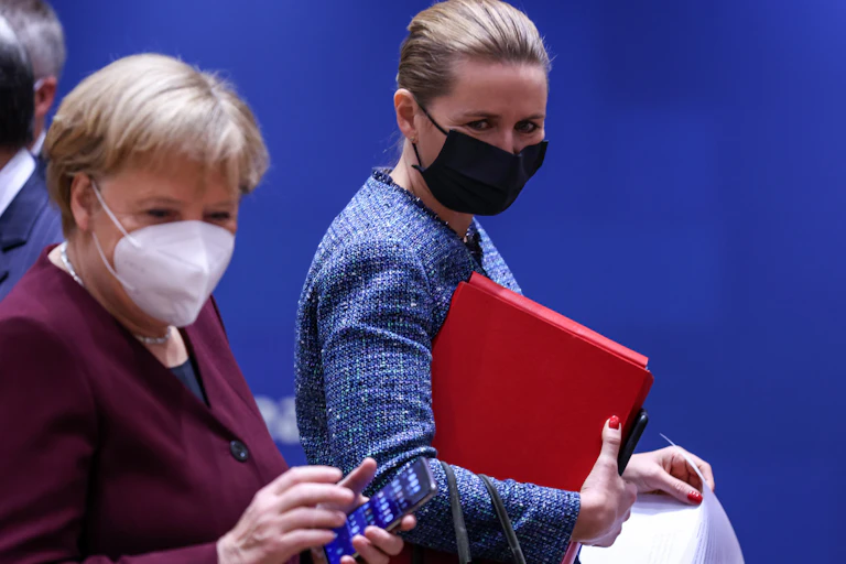 Danish Prime Minister Mette Frederiksen looks on at Angela Merkel during an EU meeting.