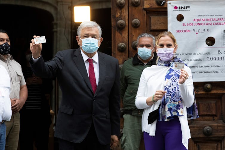 LÃ³pez Obrador holds up a piece of paper, wearing a face mask