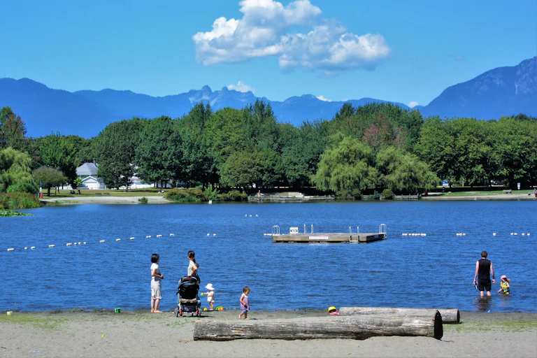 people and children on a beach and in the water at a park