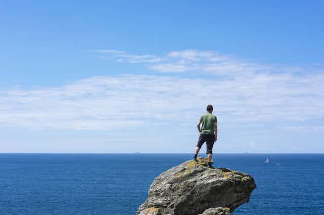 A man standing on a rock looking out over the ocean