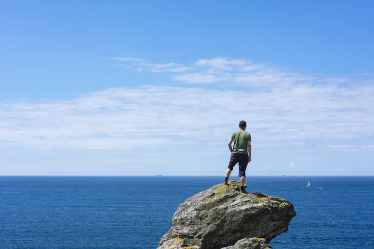A man standing on a rock looking out over the ocean