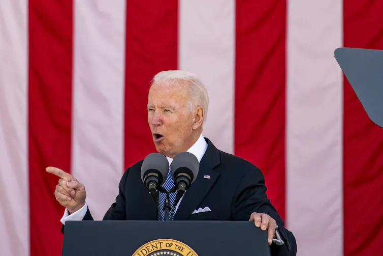 Joe Biden giving a speech in front of an American flag