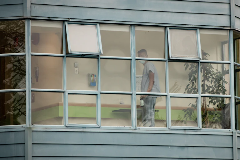 A worker is seen through a window cleaning surfaces.