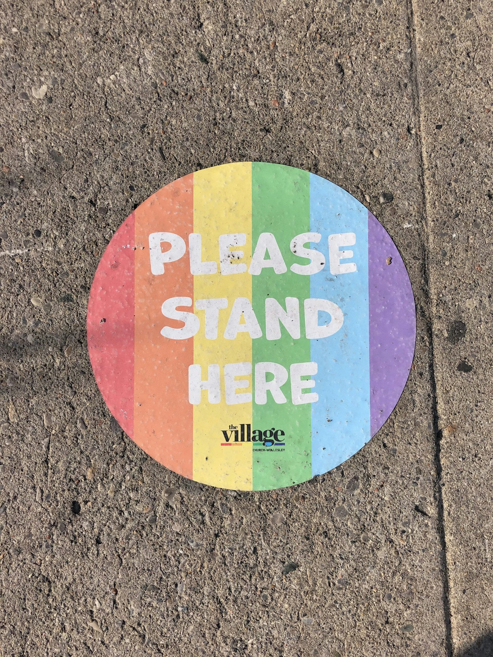 'Please stand here' social distancing sticker in Pride colors