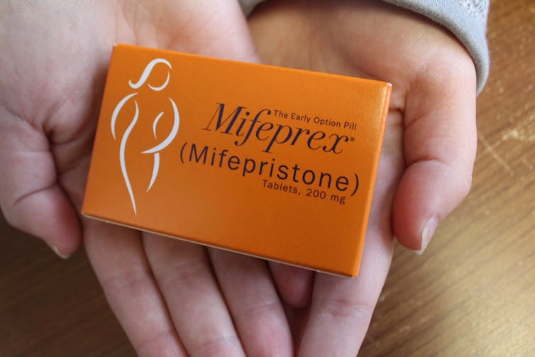 Close up of hands holding a packet of Mifepristone