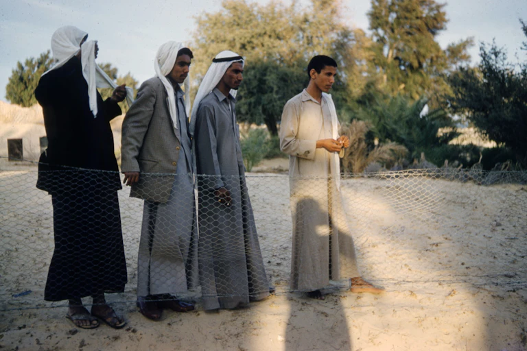 Four standing men in grey and beige robes