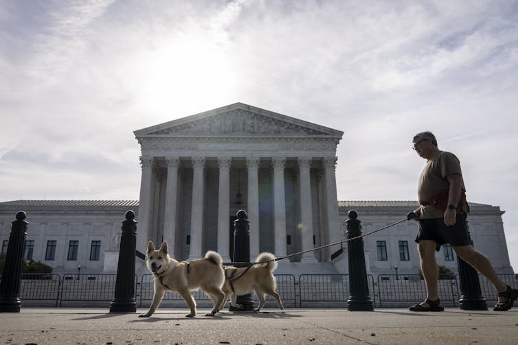 Supreme Court, with a man waking his dogs in front of it