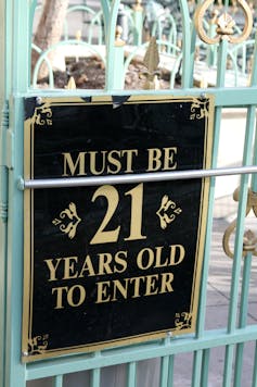 A sign on a fence saying 'Must be 21 years old to enter.'