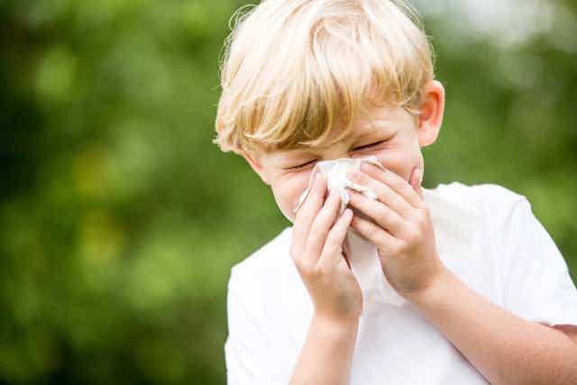 Child sneezing into tissue.