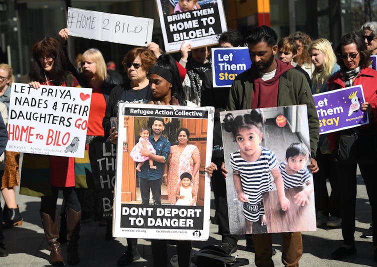 Protesters hold signs in support of the Biloela Tamil family.