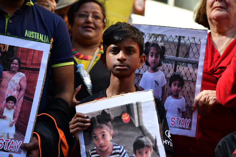 A boy holds a poster in support of the Biloela Tamil family at a 2019 rally.