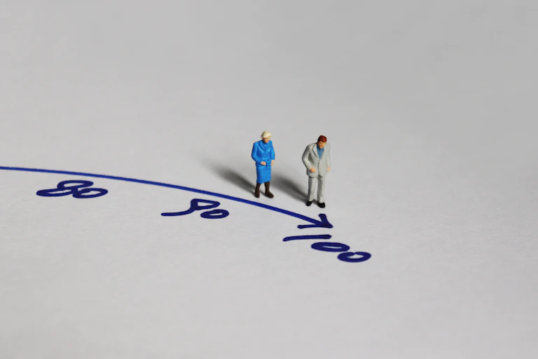 Two small figurines standing next to the number 100, to illustrate longevity.
