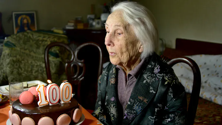 Une femme centenaire souffle sur des chandelles sur son gâteau d’anniversaire