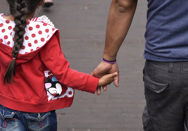 Father holds daughter's hand while walking together
