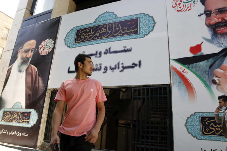 A man stands in front of large poster for Ebrahim Raisi, the conservative frontrunner in Iran's election.