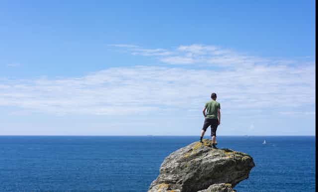 Un homme debout sur une roche contemple la mer