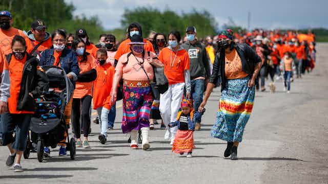 Large group of people wearing orange walk down the road