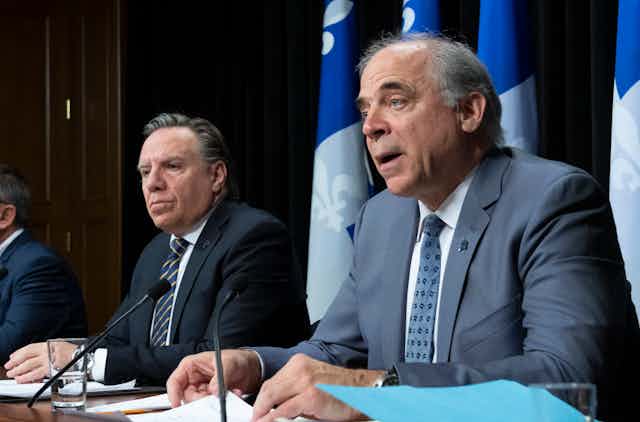 François Legault et Pierre Fitzgibbon assis côte à côté devant les drapeaux du Québec.