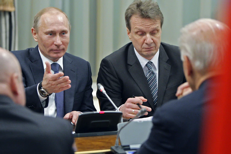 Vladimir Putin gestures with his hand at Joe Biden, whose back is turned, while sitting at a table in Moscow in 2011