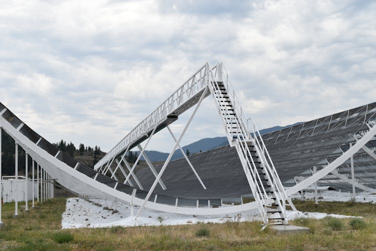 A large white and black satellite dish shaped like a half-pipe.
