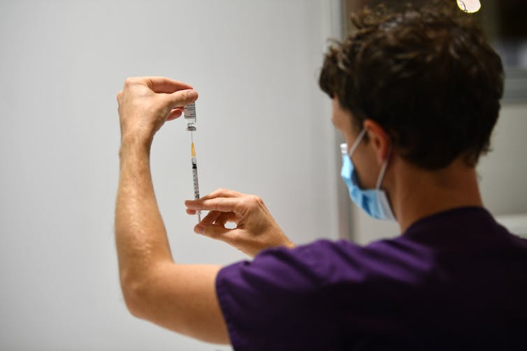 A man prepares a syringe with the AstraZeneca vaccine.