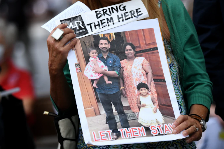A poster, depicting the Biloela family, with a caption that reads "Let they stay"
