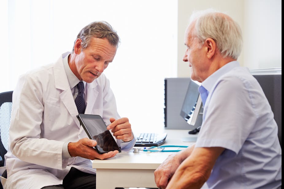 Doctor uses an iPad to explain an elderly man's diagnosis.