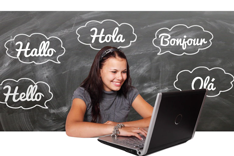 A girl at a computer surrounded by speech bubbles saying 'hello', 'hallo', 'hola', 'bonjour' and 'ola'