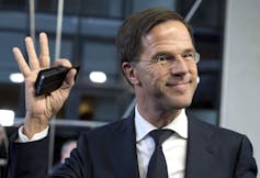 A man in a suit and tie waves