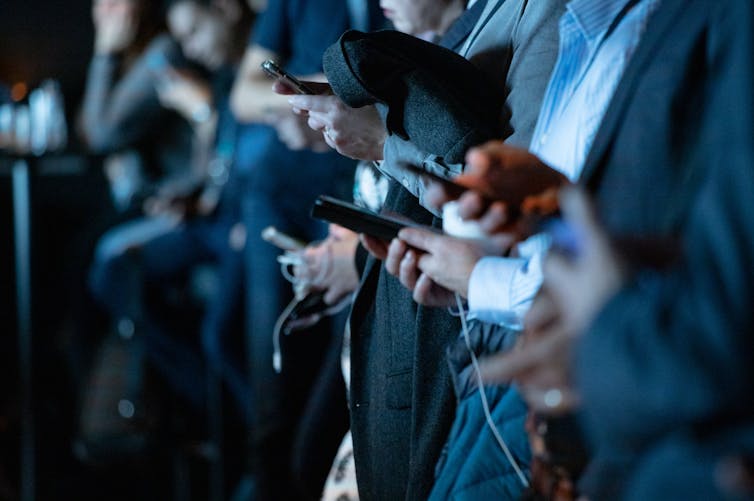 People dressed in suits look at their phones