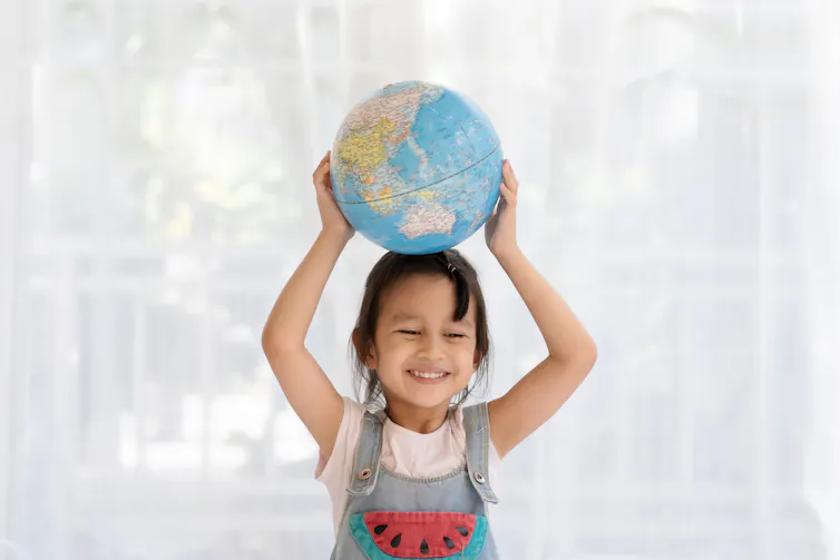 A young girl holding a globe on her head