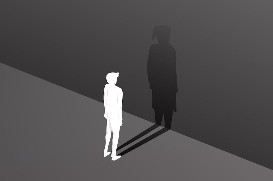 Silhouette of male and his bigger shadow as a female against a wall.