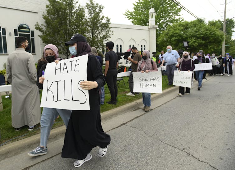 Students carry signs that say HATE KILLS and SHE WAS HUMAN