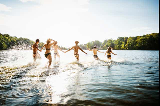 Group of people wading into lake on a sunny day