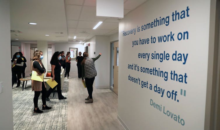 A tour group passes by a quote from Demi Lovato that's affixed to a wall at a drug recovery center.