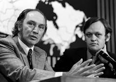Pierre Trudeau speaks as Jean Chrétien sits beside him.