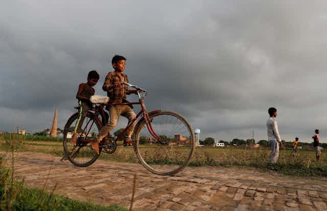 Indian children riding on a bike.