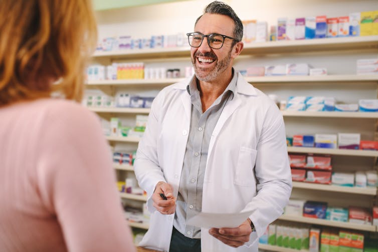 A male pharmacist talks with a female customer.