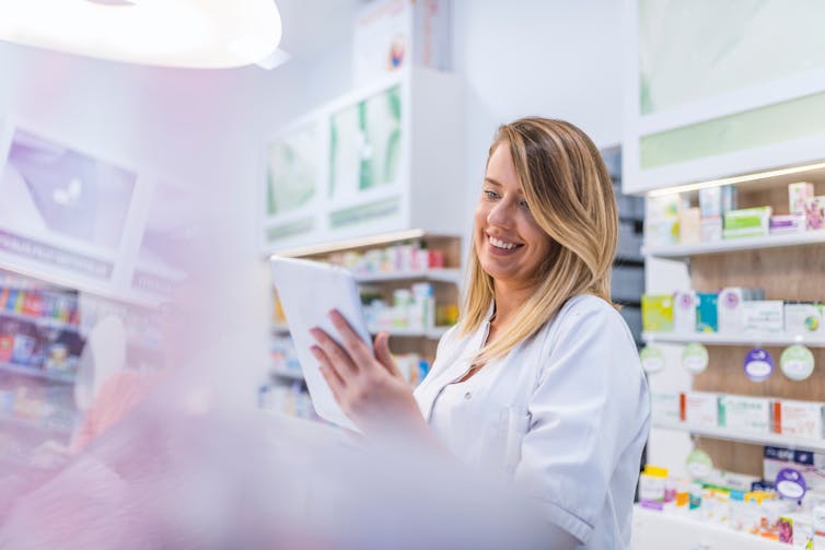 A young female pharmacist uses a tablet computer.