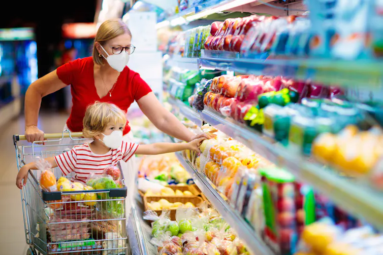Mother and child shop for vegetables at the supermarket.