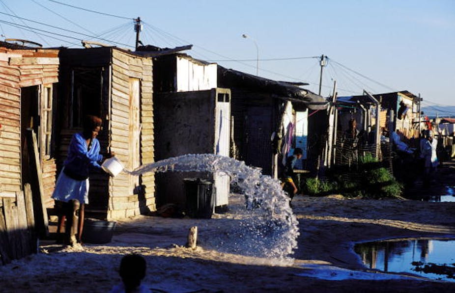 A girl throws out water from a bucket into the street in a shackland in Khayelitsha, a poor black township in Cape Town. 