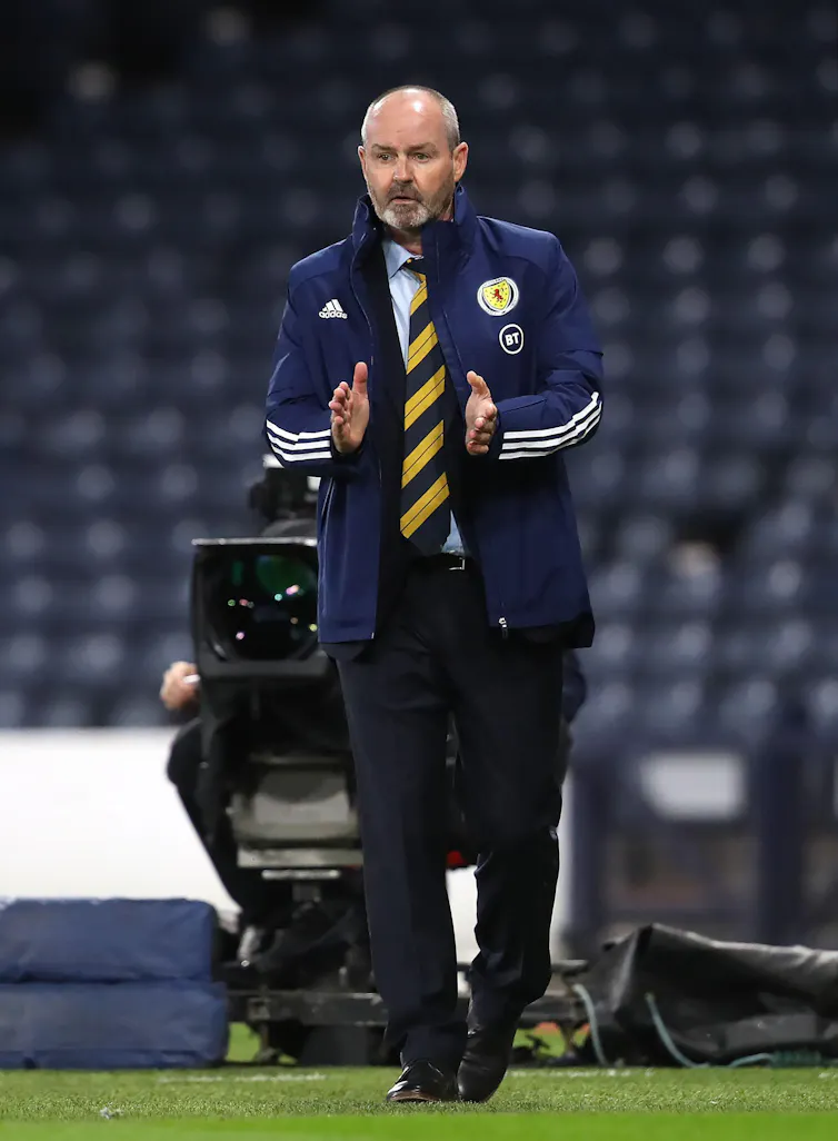 Scotland team manager Steve Clarke wearing a striped navy and yellow tie and a blue jacket on a football pitch