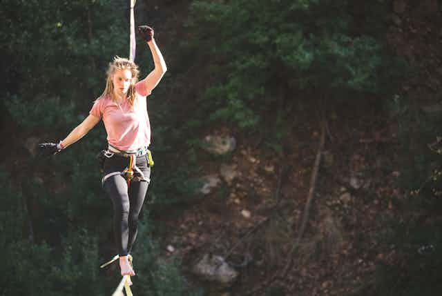 Woman on balancing on a tightrope with a harness